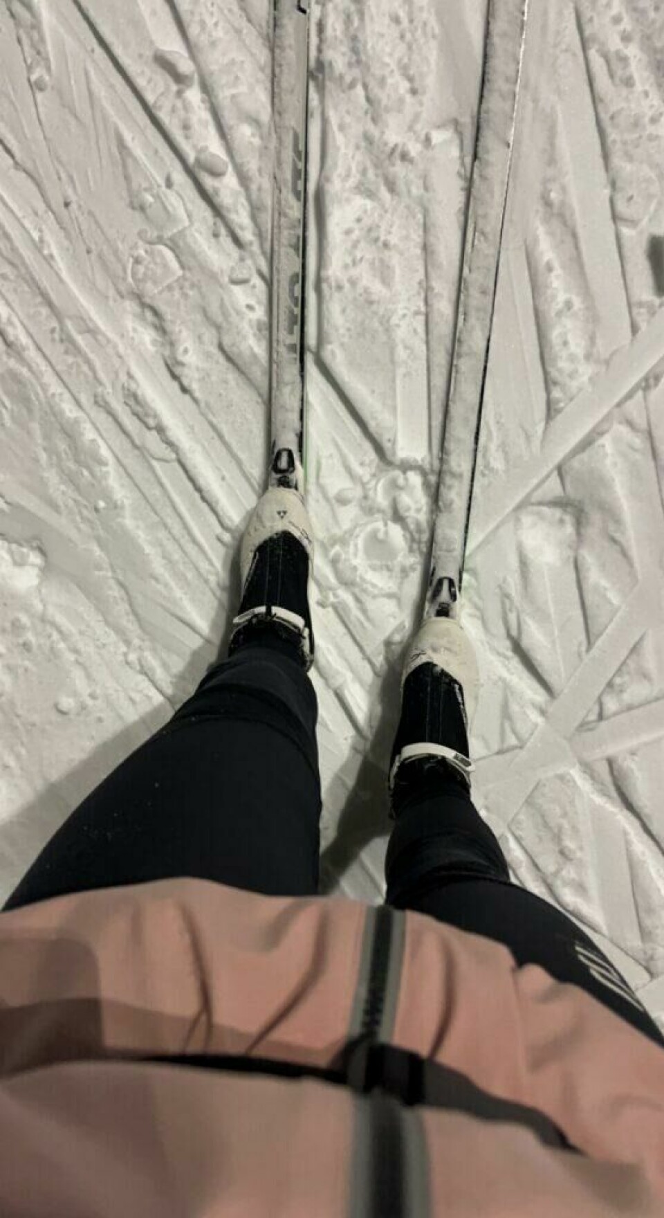 Undertegnede har ikke selv felleski(enda), som er skiene eksperten Ingeborg Scheve anbefaler til de aller fleste på grunn av egenskaper på føre av alle slag. Bilde av dame med smørefrie ski på føttene kledd i skiklær fra Dæhlie og Twentyfour. Ski og skisko er fra Fischer. Damen står med skiene på i skispor ute en kveld. Hun har på seg en rosa jakke og svarte skibukser, hvite og svarte skisko og skiene er hvite med grønne detaljer. Eksperten i saken er Ingeborg Scheve fra langrenn.com og hun forteller hvorfor hun anbefaler 90% av skigåere å kjøpe felleski heller enn smøreski og smørefrie ski.