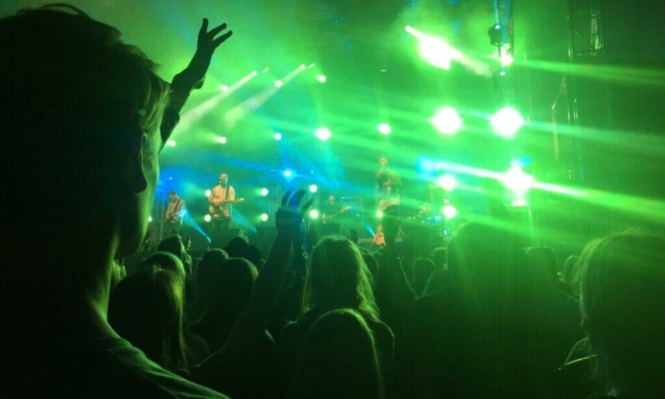 Oslos konsertliv har rykte på seg for å være bedre enn det du finner i både Stockholm og København. (Foto: Foap / VisitNorway) Konsertliv i Oslo, grønne neonlys og personer med hendene i været som danser til musikk fra band på scene i bakgrunnen.