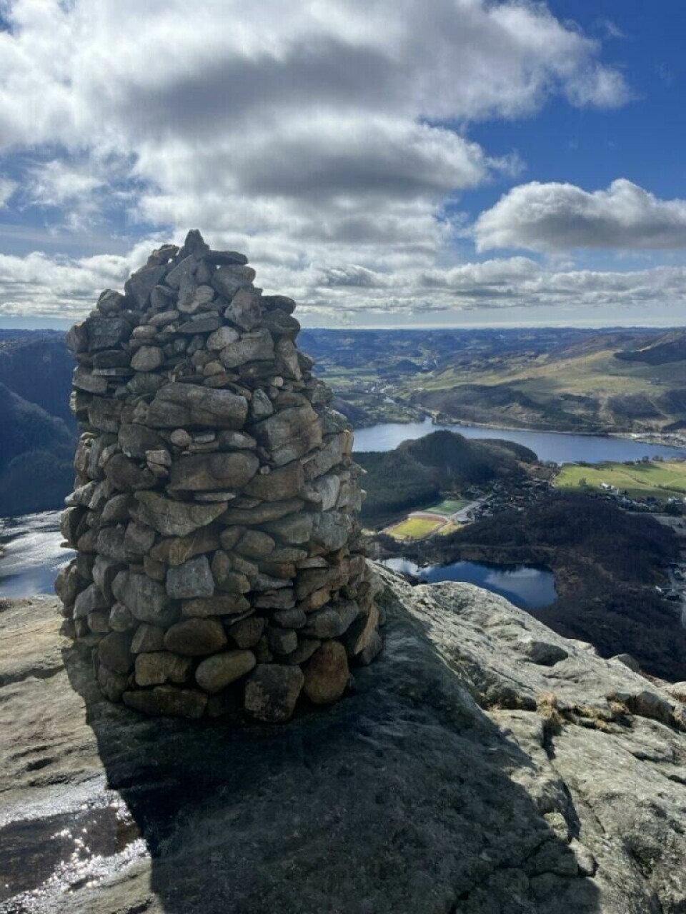 Skal du på fjelltur, men usikker på hvor? Vi viser deg 11 fjellturer, hvor du, på de aller fleste, ikke må gå i kø for å nå toppen. Et steinlagt vardetårn står majestetisk på toppen av Storafjellet (Vikeså, Bjerkreim), med storslått utsikt utover et vakkert og kupert landskap i Rogaland. I bakgrunnen sees innsjøer, grønne åser og små bygdesamfunn spredt i dalen, med snirklete veier og åpne jorder. Skyene henger lavt, men himmelen er blå og gir bildet et klart og friskt uttrykk. Varden markerer toppen av en populær fjelltur og symboliserer mål og mestring. Fjellene strekker seg utover i horisonten og gir en følelse av frihet og rom. Skal du på fjelltur i ferien? Fra Galdhøpiggen til Lofoten; Her har du 10 tips til skjulte turperler hvor du slipper å gå i kø.