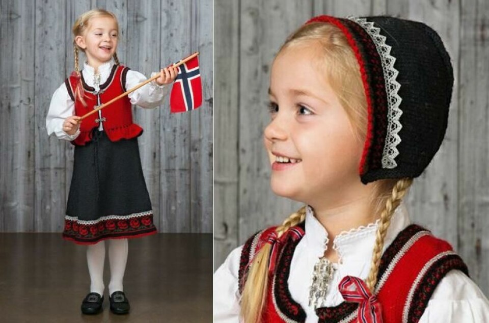 (Foto: Viking Garn) Bil de av jente i flott og klassisk festdrakt til jente med vakkert rosemønster nederst på stakken. Tilbehør til festdrakten er en kyse med blondekant. Her finner du strikkeoppskrift på den flotte festdrakten som du selv kan strikke til årets 17. mai.