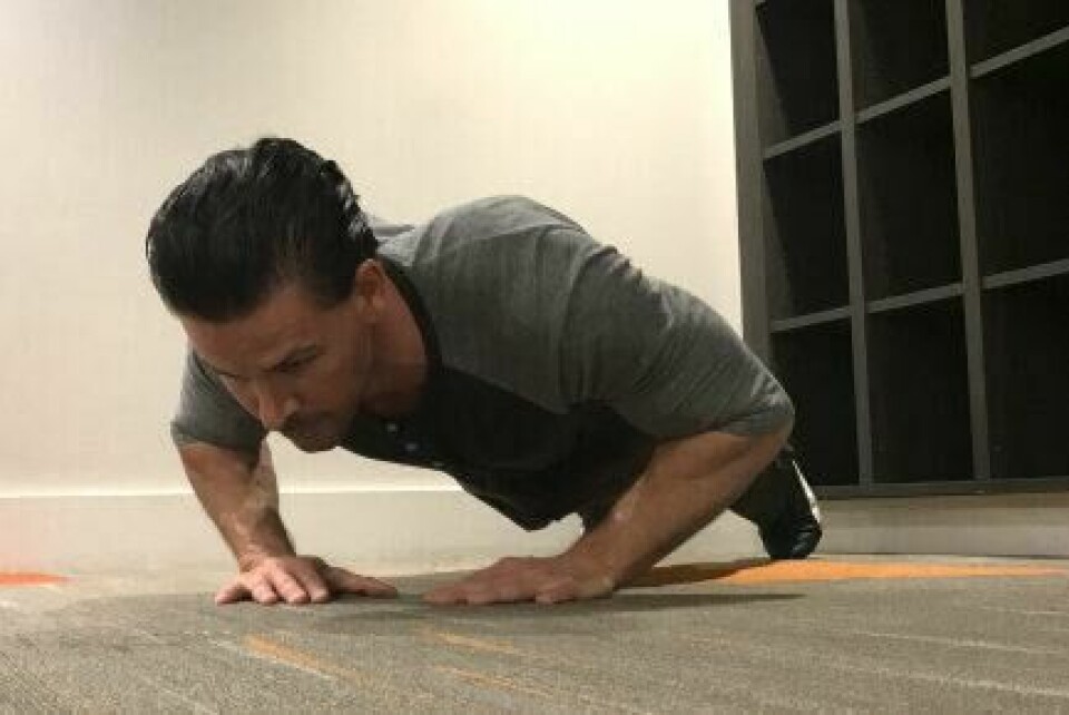 Diamond push-ups: En riktig utført push-up starter med en korrekt «planke». Det er kun brystkassen som så vidt skal berøre underlaget, mens hofte, midje, knær, og resten av kroppen IKKE skal kollapse ned mot underlaget eller forandre posisjon underveis. (Foto: Cornelis Elander) Bilde av personlig trener Cornelis Elander som trener armhevinger/ diamond push-ups på treningsmatte. Han har på seg en grå t-skjorte, en blå treningsbukse og befinner seg i et treningsrom. Dette er en styrkeøvelse med fordeler for hele kroppen, og er en av styrkeøvelsene i vårt 30-dagers gratis treningsprogram og styrkeprogram.
