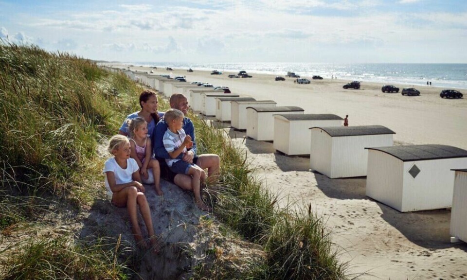 Løkken er en klassisk badeby på Nordjyllands vestkyst, hvor du finner en av Danmarks beste strender og de karakteristiske hvite badehusene. (Foto: Niclas Jessen / VisitDenmark) familie som speider utover stranden på løkken med utsikt til de hvite badehusene i den danske badebyen