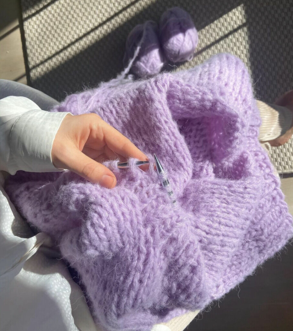 Du kan også strikke genseren i et mer fluffy alternativ. Her har Runa strikket genseren i Sandnes Garn Børstet Alpakka. Foto: Runa Sommerfelt Lilla strikket genser i fluffy garn. Dame som holder strikketøy. Strikkeoppskrift for nybegynnere.