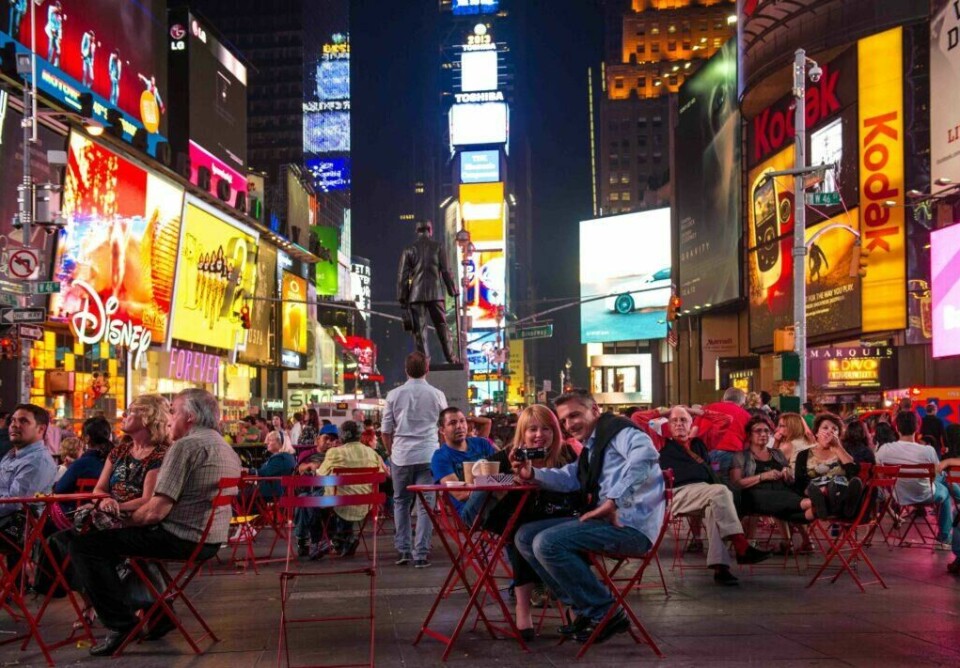 Mange turister tar seg en tur til Times Square på Manhattan for å oppleve folkelivet midt i New York. Times Square Manhattan New York uteservering mange folk og store billboards
