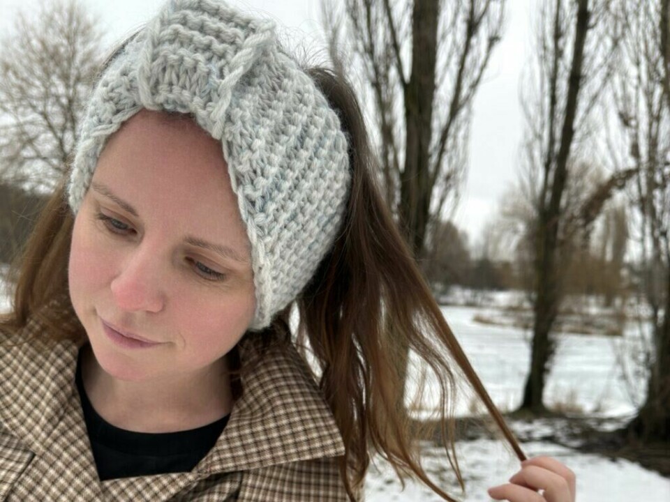 La deg inspirere av dette tidløse pannebåndet – perfekt for både nybegynnere og erfarne strikkere. Kreativ enkel, strikk med Aurora og Miriam' En e-bok med enkle strikkeoppskrifter – perfekt for deg som vil lære å strikke eller bruke opp restegarnet ditt! Nærbilde av en kvinne som ser ned mens hun fikler med håret. Hun har på seg et tykt, strikket pannebånd i lysegrått med flettemønster. Vintertrær og snøfylte omgivelser utgjør en rolig bakgrunn. Pannebåndet gir et sofistikert og samtidig rustikt uttrykk, ideelt for nybegynnere som vil mestre flettestrikk.