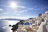 Santorini er spesielt kjent for sin caldera med hvite hus og blå tak. Her avbildet i solskinn med nærliggende øyer og hav i bakgrunnen.