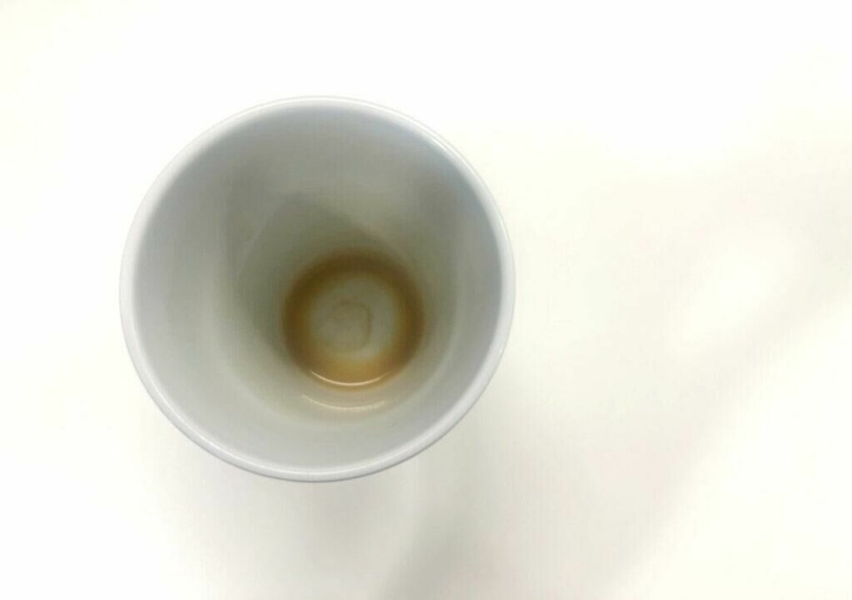 Informasjon om at det å drikke kaffe på tom mage ikke er sunt har spredt seg som ild i tørt gress på sosiale medier. Ekspertene sier derimot at du skal innta veldig skadelige stoffer før magens forsvar blir ødelagt, og at det ikke er noen tydelig forskning som tilsier at kaffe på tom mage er skadelig. (Foto: ABC Guider) Bilde av tom kaffekopp på hvitt bord til artikkel som gir deg svaret på om det er lurt å drikke kaffe på tom mage.