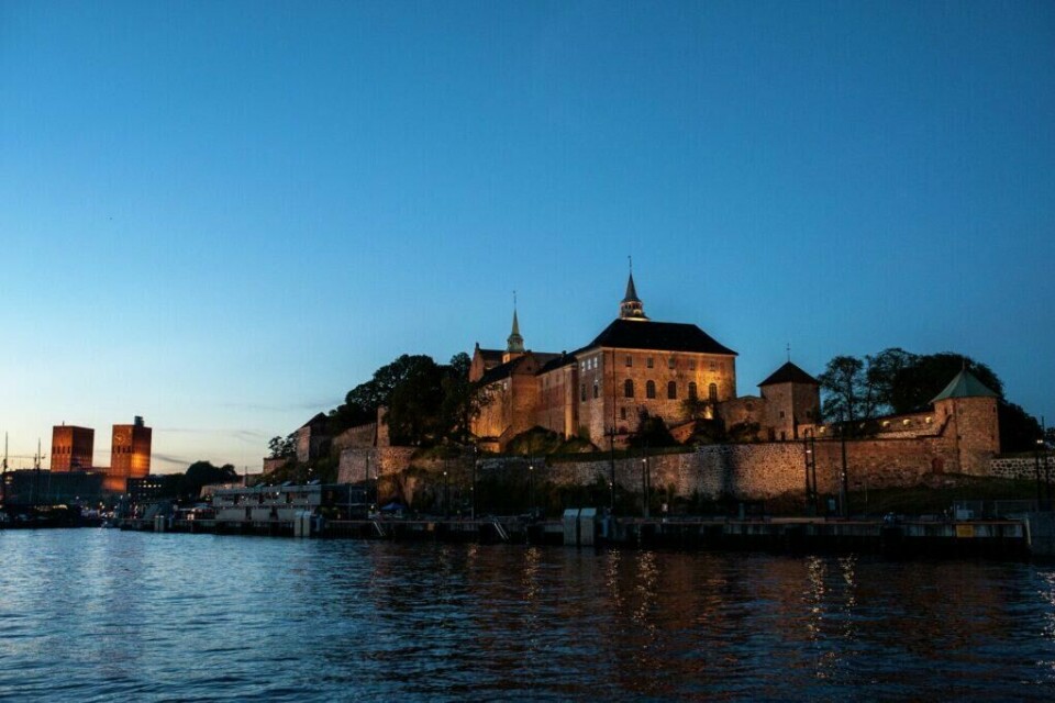 Akershus Festning i solnedgang med Rådhuset i bakgrunnen. (Foto: VisitOSLO/Thomas Johannessen) Akershus festning ligger på Aker Brygge helt nede ved havnen og Oslofjorden med en nydelig utsikt og godt utvalg arrangement og kunst på egne museum.