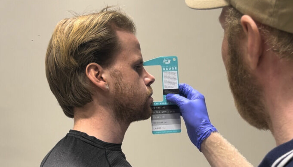 Hvor lite trening og aktivitet som skal til for å få en enorm helseeffekt, er underkommunisert av helsemyndighetene, sier Wisløff. Bildet viser to menn i et test- eller klinikkmiljø. Personen til venstre står i profil og blåser ut kinnene mens han ser rett frem. Han har lysebrunt hår og er iført en svart, tettsittende treningsskjorte. Personen til høyre, delvis sett bakfra, holder opp et målekort foran ansiktet til den første personen. Han har på seg blå engangshansker og en beige caps. Målekortet ser ut til å være et 'mask gauge'-verktøy som brukes til å bestemme riktig størrelse på pustemasker, med størrelser merket som 'XS', 'S', 'M', og 'L'. Dette er trolig en del av forberedelsene til en VO2-maks-test, der det er viktig at testmasken passer godt til ansiktet. Bakgrunnen er nøytral med en beige vegg og uten visuelle forstyrrelser, noe som antyder at bildet er tatt i et kontrollert, klinisk eller forskningsrelatert miljø. Har du en god kondisjon og høy VO2-maks «kan du fortsette å røyke og drikke hver dag». Dette sier forskningen om «den ene tingen du kan gjøre som betyr mest for din fremtidige helse».