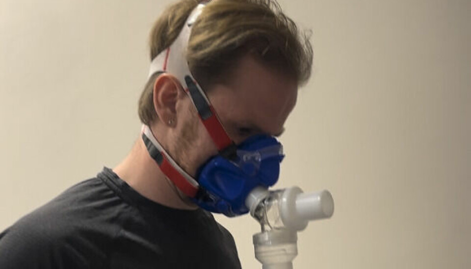 Jenssen sier at når vi er rundt 35 så begynner kondisjonen vår også å gå gradvis nedover, men at man faktisk kan ha den høyeste VO2-maksen man selv har mulighet for å få, selv om man er 40 år. Bildet viser en mann i svart treningstøy som står i et innendørs testmiljø, iført en blå pustemaske forbundet med en plastslange. Masken dekker nese og munn og er festet til hodet med hvite og røde stropper. Slangen som er koblet til masken leder inn i et apparat som trolig måler oksygenopptak, typisk brukt i en VO2-maks-test. Mannen ser nedover med et konsentrert uttrykk, og bakgrunnen er enkel og ensfarget beige, noe som forsterker det kliniske og fokuserte miljøet bildet er tatt i. Dette er mest sannsynlig en del av testforberedelsene eller en pause underveis i testen. Har du en god kondisjon og høy VO2-maks «kan du fortsette å røyke og drikke hver dag». Dette sier forskningen om «den ene tingen du kan gjøre som betyr mest for din fremtidige helse».