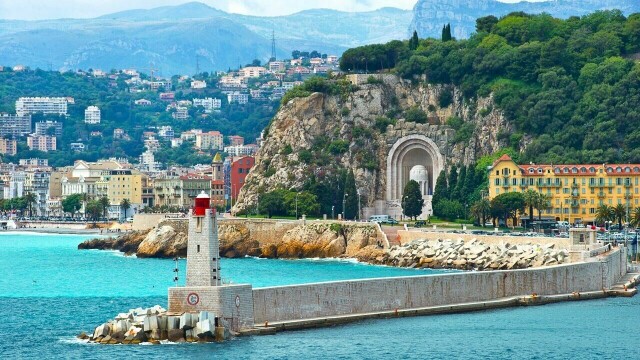 Port de Nice (havnen i Nice) med den karakteristiske moloen og fyret i forgrunnen. I bakgrunnen kan du se Monument aux Morts, et krigsminnesmerke hugget inn i klippen ved Quai Rauba-Capeù. (Foto: Colourbox)