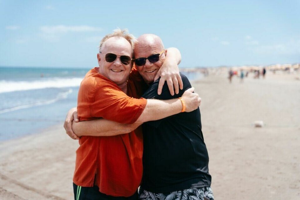 Per Sandberg og broren besøker Gran Canaria i ny sesong av Charterfeber. (Foto: Viaplay) Bilde av Per Sandberg og broren Roar Sandberg som gir hverandre en klem på en strand på Gran Canaria. Her finner du årets Charterfeber-hotell. Sjekk hvor blant annet Harstad-gjengen og charter-svein bor på Gran Canaria.